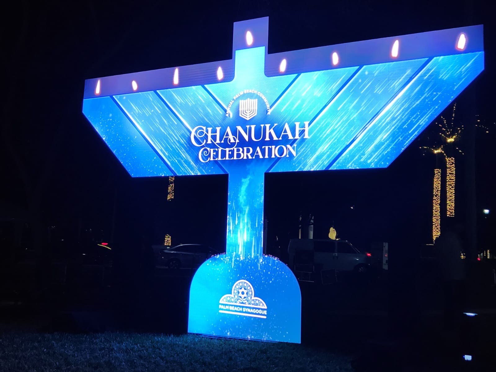 Large outdoor menorah built as an illuminated LED structure glowing blue at night